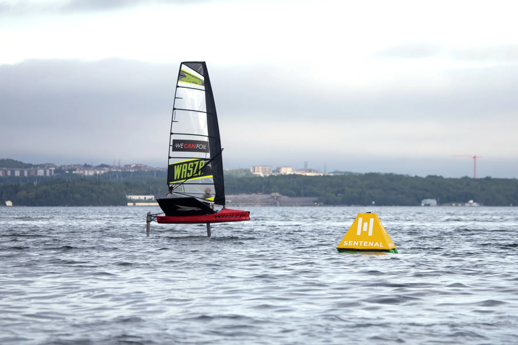 A yellow Sentenal holding position with a foiling dinghy behind it