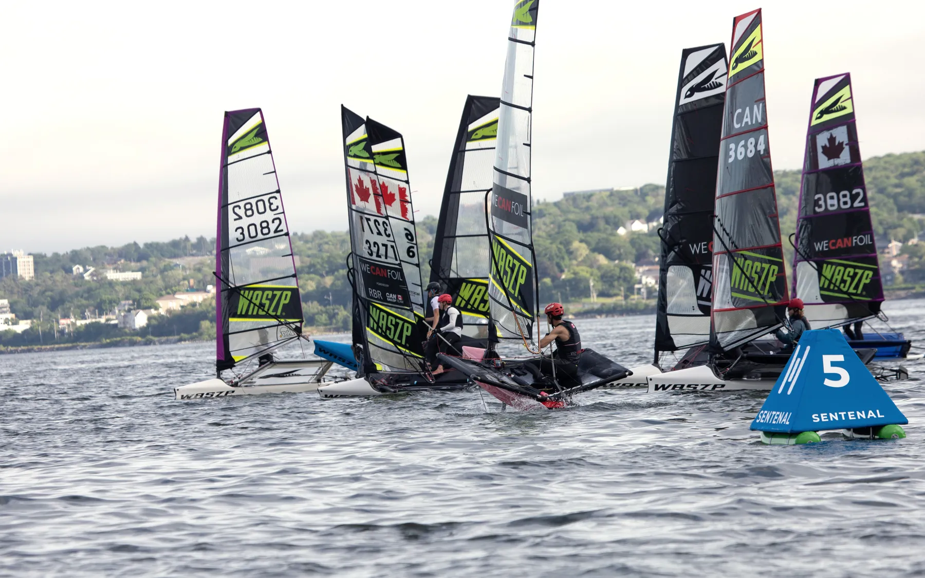 Foiling dinghies rounding a blue Sentenal, shoulder to shoulder
